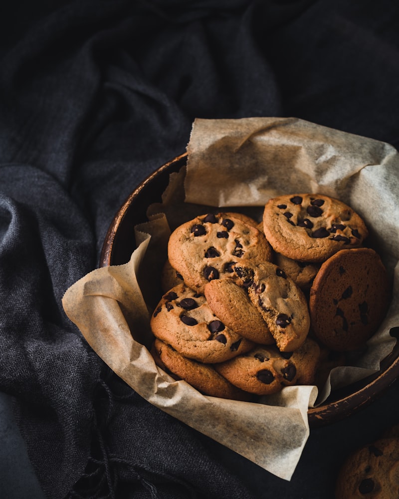 Delicate porcelain cup filled with rich espresso with perfect crema placed next to a chocolate chip cookie on a beige saucer